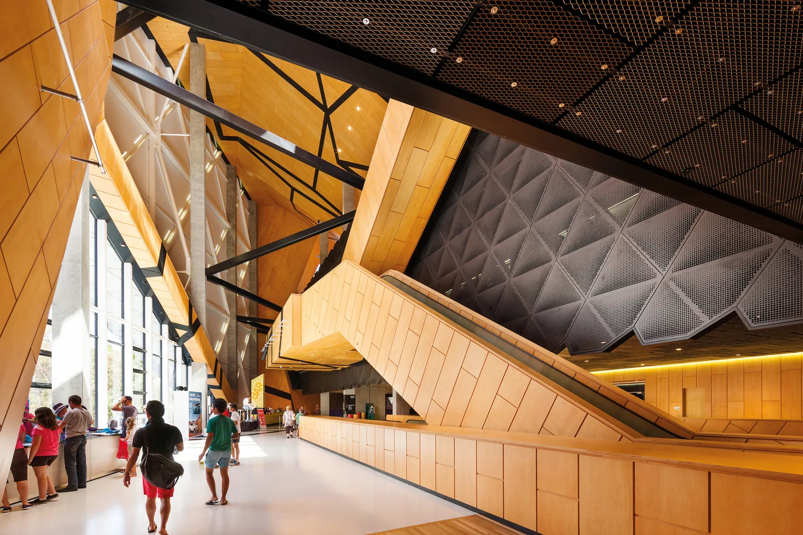 Wide interior of a multi-level shopping mall with a central atrium, glass balustrades, escalators and storefronts along the corridors